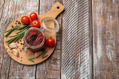 Photo of Delicious sun dried tomatoes, fresh vegetables, rosemary and garlic on wooden table, top view. Space for text