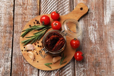 Photo of Delicious sun dried tomatoes, fresh vegetables, rosemary and garlic on wooden table, top view