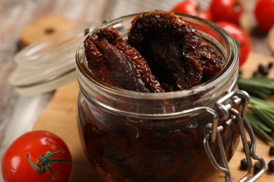 Photo of Delicious sun dried tomatoes in jar on table, closeup