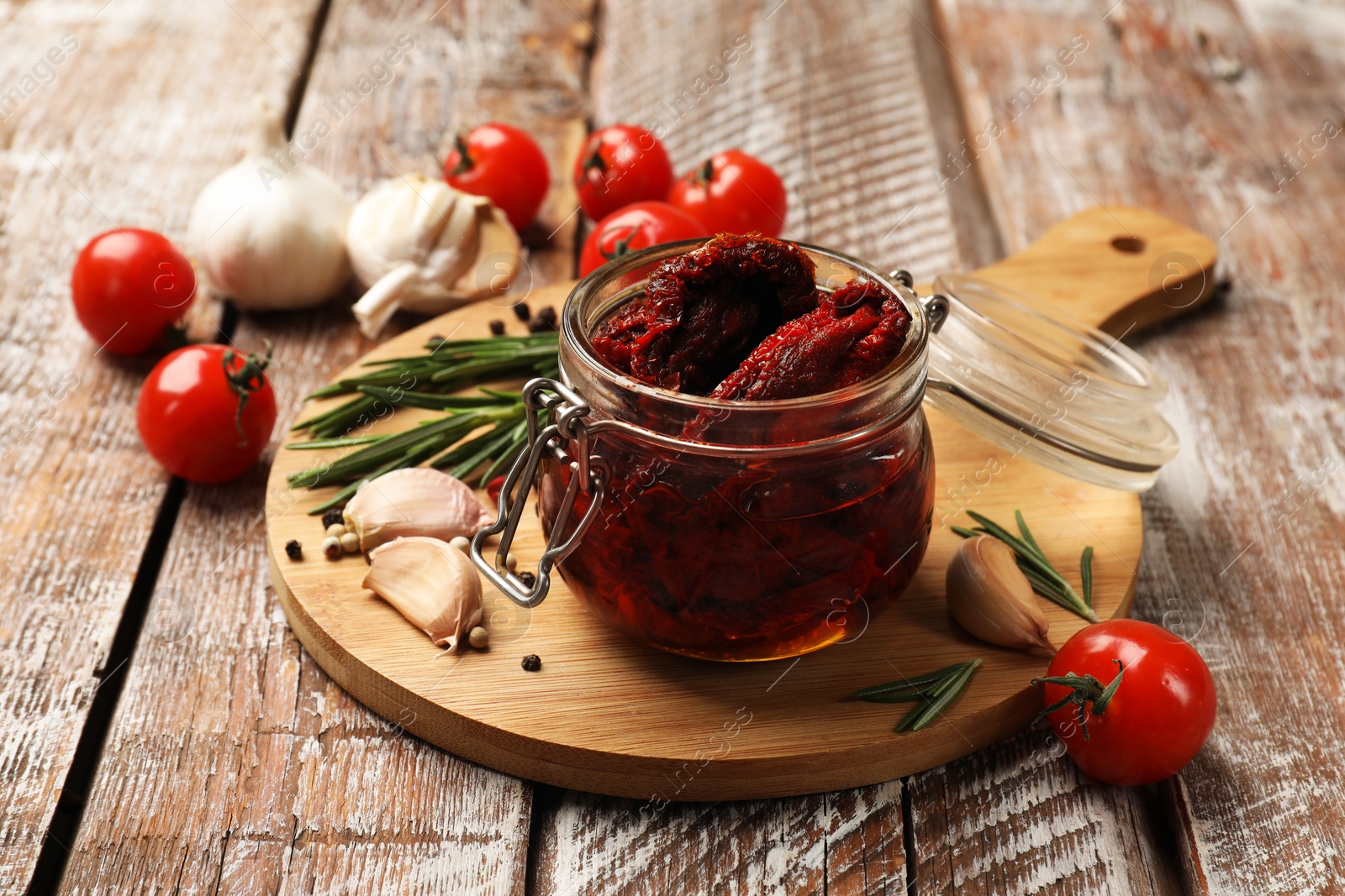 Delicious sun dried tomatoes, fresh vegetables, rosemary and garlic on wooden table, closeup Photo of Delicious sun dried tomatoes, fresh vegetables, rosemary and garlic on wooden table, closeup