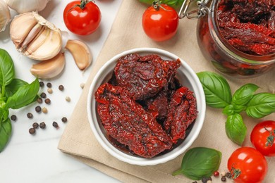 Photo of Delicious sun dried tomatoes, fresh vegetables, basil and garlic on white table, flat lay