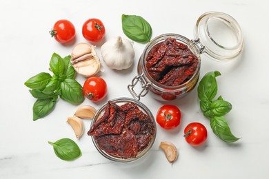Photo of Delicious sun dried tomatoes, fresh vegetables, basil and garlic on white table, flat lay