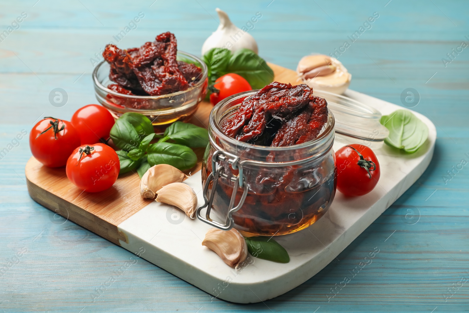 Delicious sun dried tomatoes, fresh vegetables, basil and garlic on blue wooden table, closeup Photo of Delicious sun dried tomatoes, fresh vegetables, basil and garlic on blue wooden table, closeup
