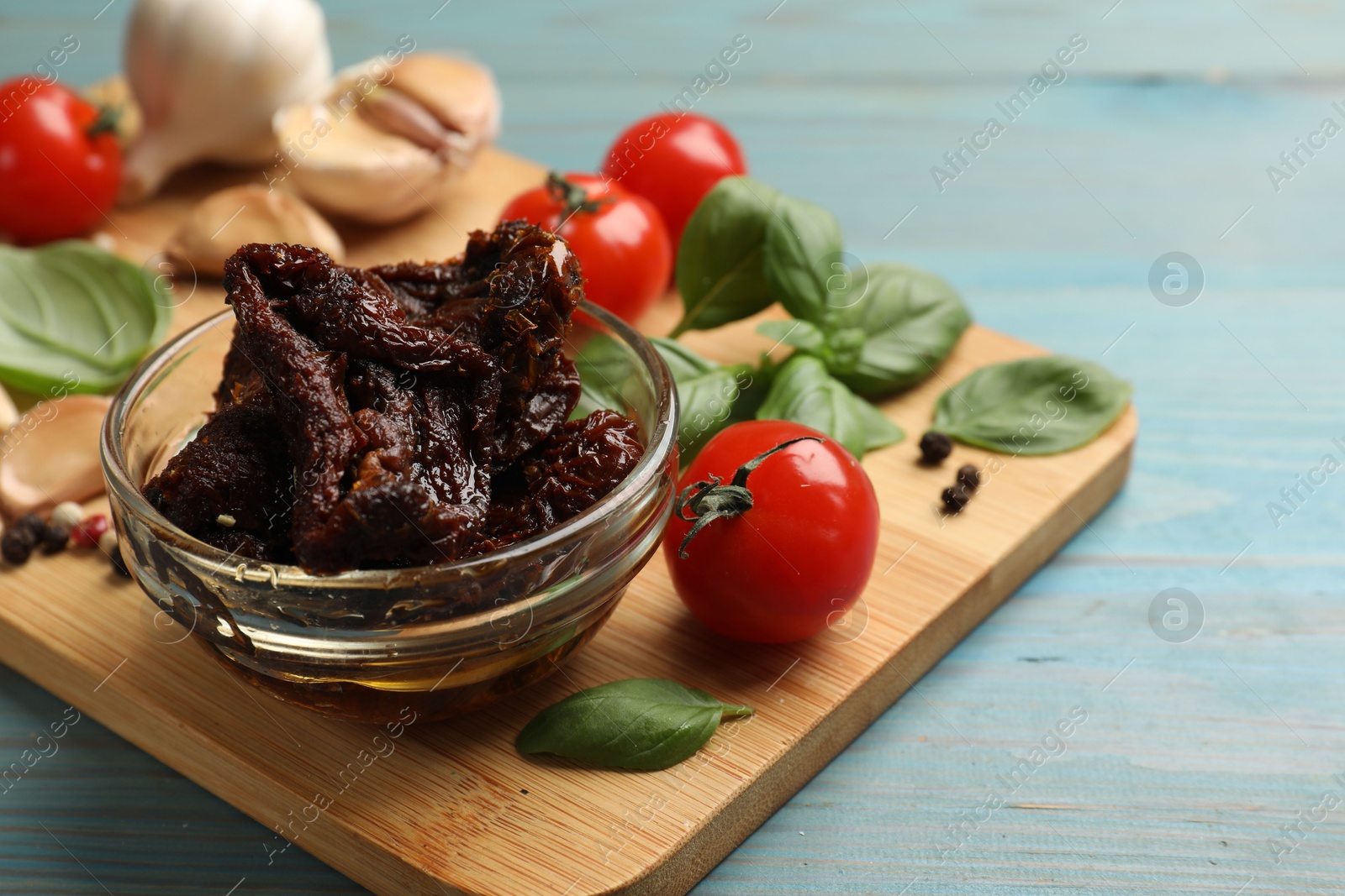 Delicious sun dried tomatoes, fresh vegetables, basil and garlic on blue wooden table, closeup Photo of Delicious sun dried tomatoes, fresh vegetables, basil and garlic on blue wooden table, closeup