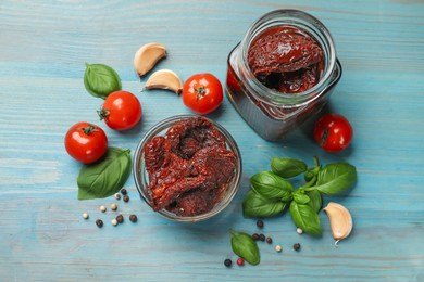 Photo of Delicious sun dried tomatoes, fresh vegetables, basil and garlic on blue wooden table, flat lay