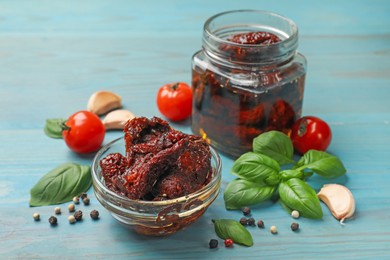 Photo of Delicious sun dried tomatoes, fresh vegetables, basil and garlic on blue wooden table, closeup