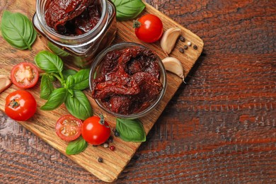 Photo of Delicious sun dried tomatoes, fresh vegetables, basil and garlic on wooden table, top view