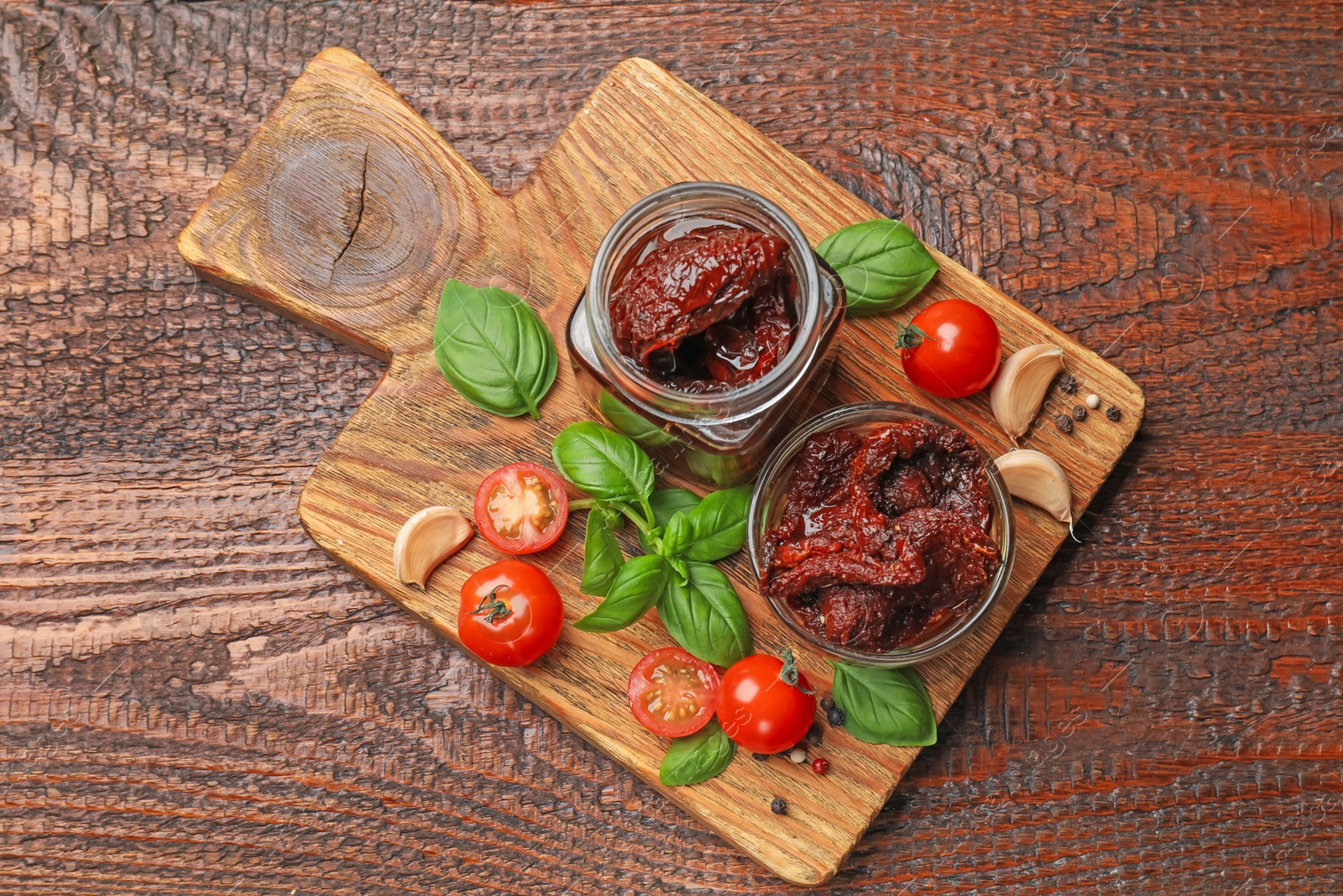 Delicious sun dried tomatoes, fresh vegetables, basil and garlic on wooden table, top view Photo of Delicious sun dried tomatoes, fresh vegetables, basil and garlic on wooden table, top view
