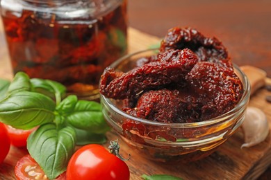 Photo of Delicious sun dried tomatoes, fresh vegetables, basil and garlic on wooden table, closeup