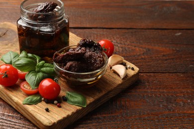 Photo of Delicious sun dried tomatoes, fresh vegetables, basil and garlic on wooden table, closeup. Space for text