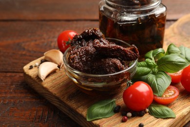 Photo of Delicious sun dried tomatoes, fresh vegetables, basil and garlic on wooden table, closeup