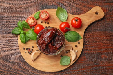 Photo of Delicious sun dried tomatoes, fresh vegetables, basil and garlic on wooden table, top view