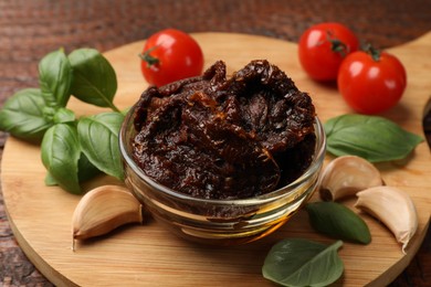 Photo of Delicious sun dried tomatoes, fresh vegetables, basil and garlic on wooden table, closeup