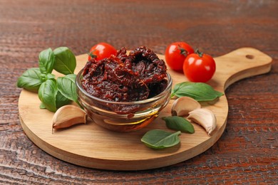 Photo of Delicious sun dried tomatoes, fresh vegetables, basil and garlic on wooden table, closeup