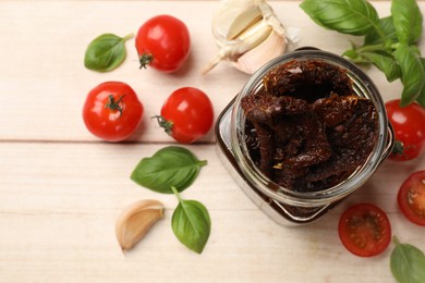 Photo of Delicious sun dried tomatoes, fresh vegetables, basil and garlic on white wooden table, flat lay