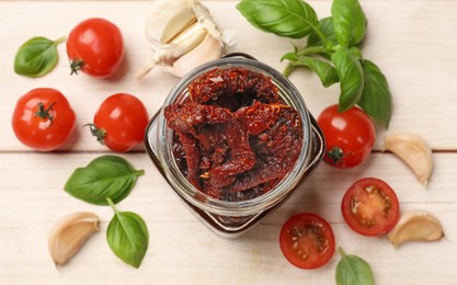 Photo of Delicious sun dried tomatoes, fresh vegetables, basil and garlic on white wooden table, flat lay