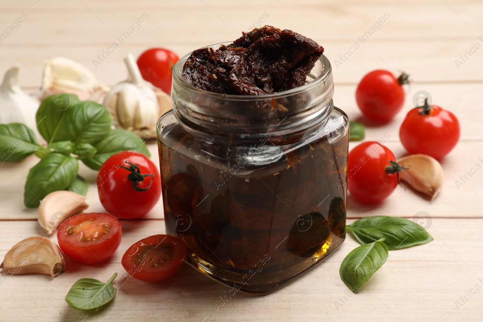 Delicious sun dried tomatoes, fresh vegetables, basil and garlic on white wooden table, closeup Photo of Delicious sun dried tomatoes, fresh vegetables, basil and garlic on white wooden table, closeup