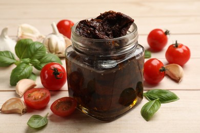 Photo of Delicious sun dried tomatoes, fresh vegetables, basil and garlic on white wooden table, closeup