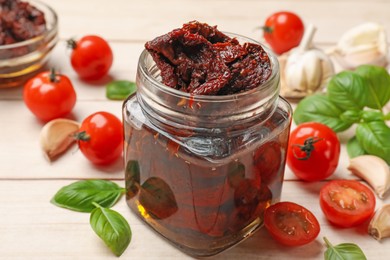 Photo of Delicious sun dried tomatoes, fresh vegetables, basil and garlic on white wooden table, closeup