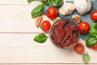 Photo of Delicious sun dried tomatoes, fresh vegetables, basil and garlic on white wooden table, flat lay. Space for text