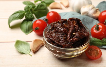Photo of Delicious sun dried tomatoes, fresh vegetables, basil and garlic on white wooden table, closeup
