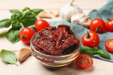 Photo of Delicious sun dried tomatoes, fresh vegetables, basil and garlic on white wooden table, closeup