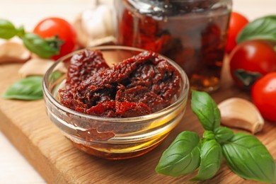 Photo of Delicious sun dried tomatoes, fresh vegetables, basil and garlic on white table, closeup