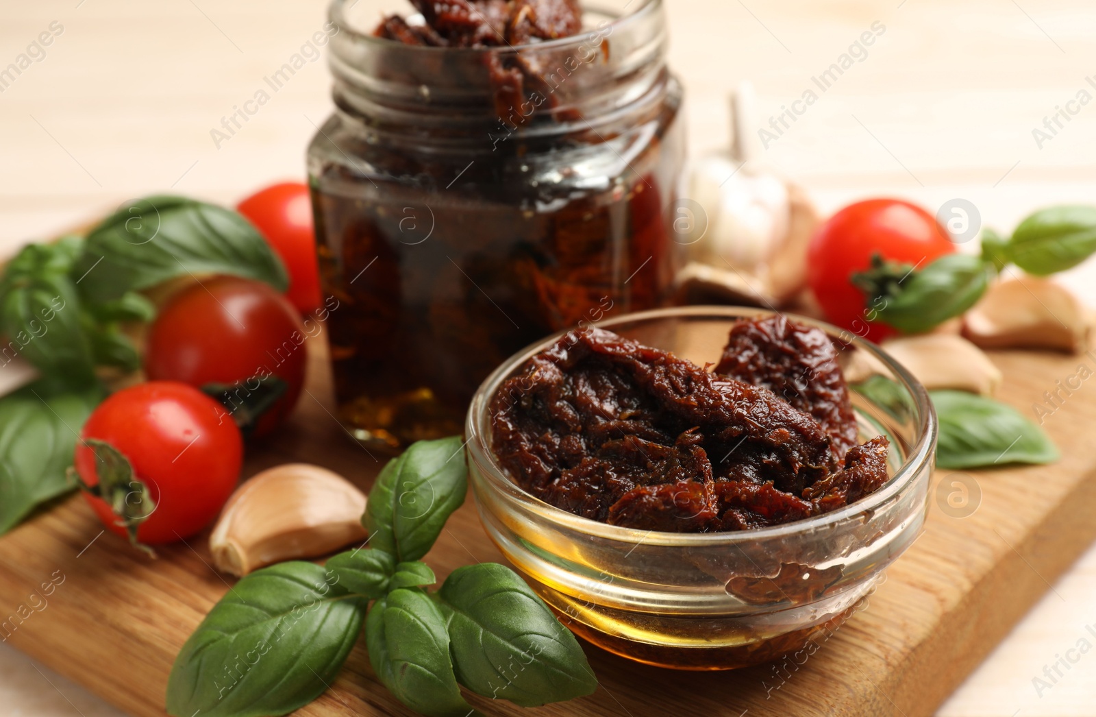 Delicious sun dried tomatoes, fresh vegetables, basil and garlic on white table, closeup Photo of Delicious sun dried tomatoes, fresh vegetables, basil and garlic on white table, closeup