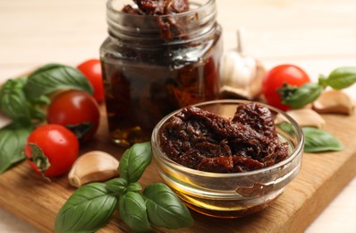 Photo of Delicious sun dried tomatoes, fresh vegetables, basil and garlic on white table, closeup