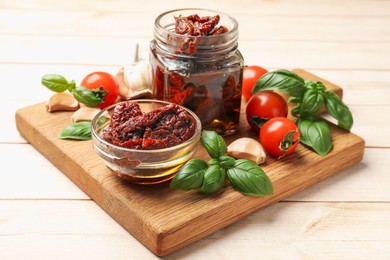 Photo of Delicious sun dried tomatoes, fresh vegetables, basil and garlic on white wooden table, closeup