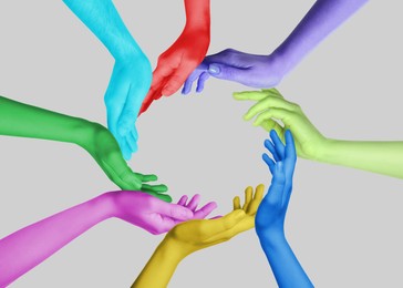 Image of People making circle with their hands painted in different colors on grey background, closeup. Unity, partnership, cooperation