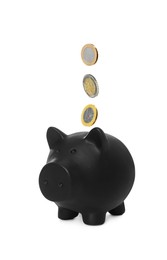 Image of Coins falling into black piggy bank on white background