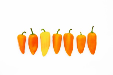 Image of Individuality, uniqueness, different. Yellow pepper among orange ones on white background, top view