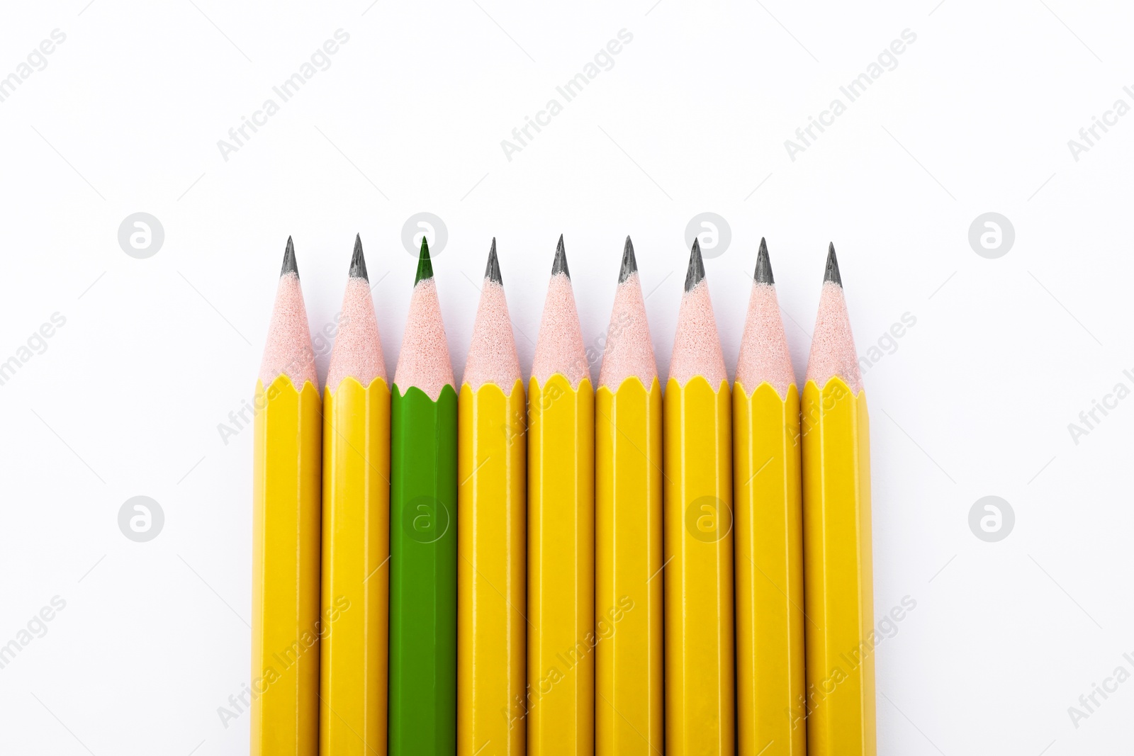 Image of Individuality, uniqueness, different. Green pencil among yellow ones on white background, top view
