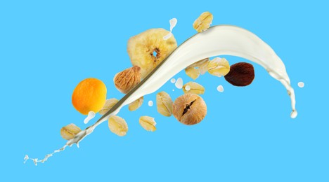 Image of Milk splash with oat flakes and dried fruits on light blue background. Banner design