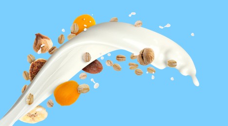 Image of Milk splash with oat flakes and dried fruits on light blue background. Banner design