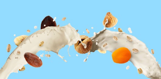 Image of Milk splash with oat flakes and dried fruits on light blue background. Banner design