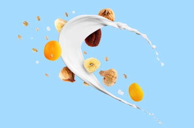 Image of Milk splash with oat flakes and dried fruits on light blue background. Healthy breakfast