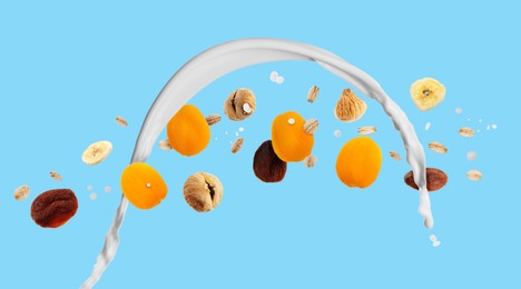 Image of Milk splash with oat flakes and dried fruits on light blue background. Banner design