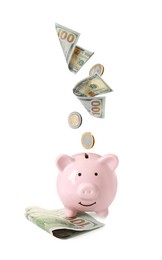 Image of Dollar bills and coins falling into pink piggy bank on white background
