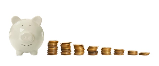 Image of Piggy bank and stacks of coins from bigger to smaller on white background