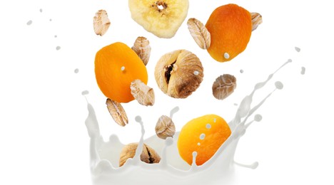 Image of Milk splash with oat flakes and dried fruits in air on white background. Healthy breakfast