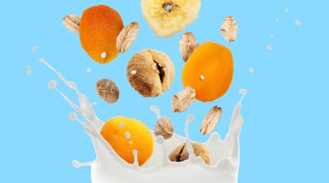 Image of Milk splash with oat flakes and dried fruits in air on light blue background. Banner design