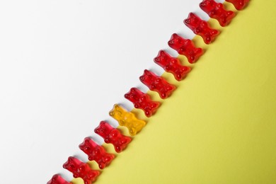 Image of Individuality, uniqueness, different. Orange jelly bear among red ones on color background, top view