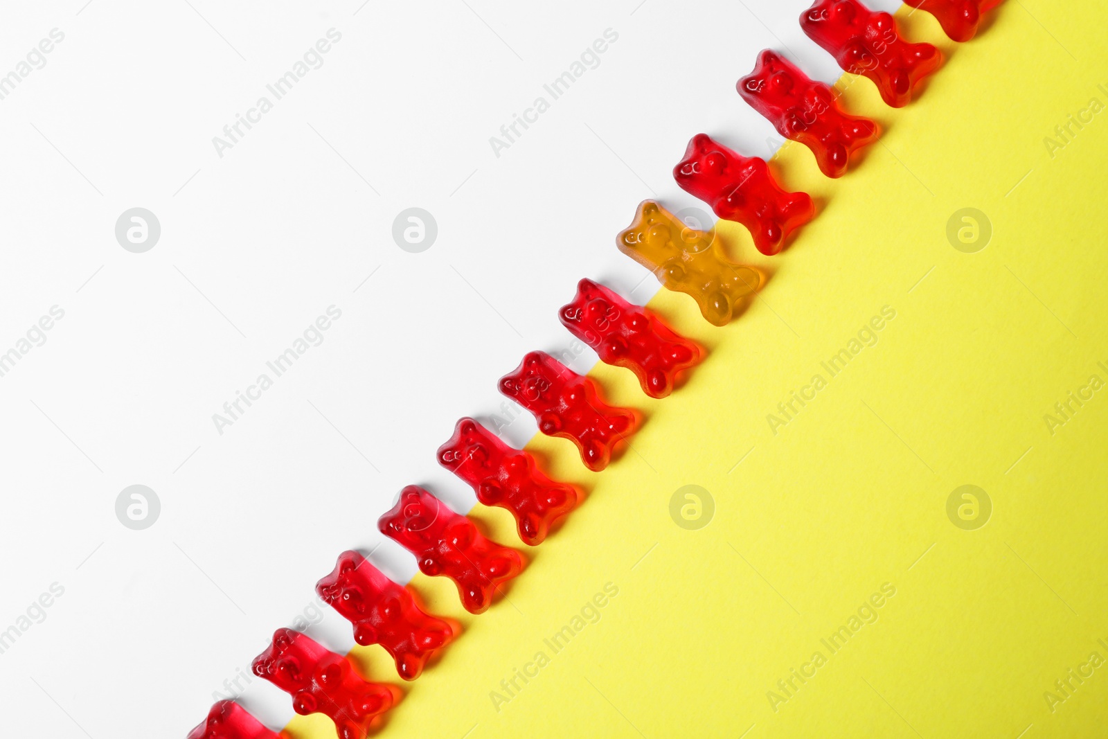 Individuality, uniqueness, different. Orange jelly bear among red ones on color background, top view Image of Individuality, uniqueness, different. Orange jelly bear among red ones on color background, top view