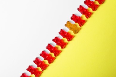 Image of Individuality, uniqueness, different. Orange jelly bear among red ones on color background, top view