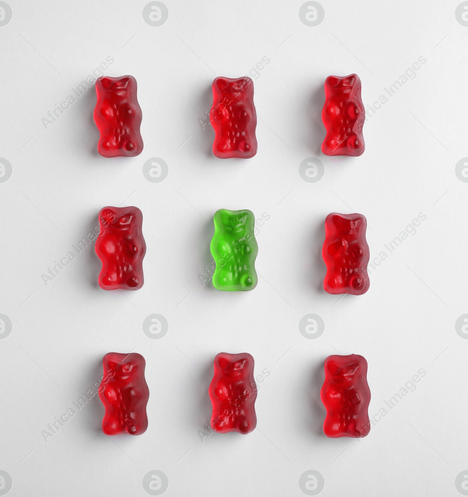 Individuality, uniqueness, different. Green jelly bear among red ones on white background, flat lay Image of Individuality, uniqueness, different. Green jelly bear among red ones on white background, flat lay