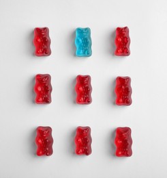 Image of Individuality, uniqueness, different. LIght blue jelly bear among red ones on white background, flat lay