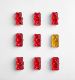 Image of Individuality, uniqueness, different. Orange jelly bear among red ones on white background, flat lay
