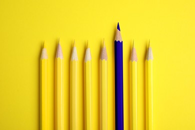 Image of Individuality, uniqueness, different. Blue pencil among yellow ones on bright background, top view